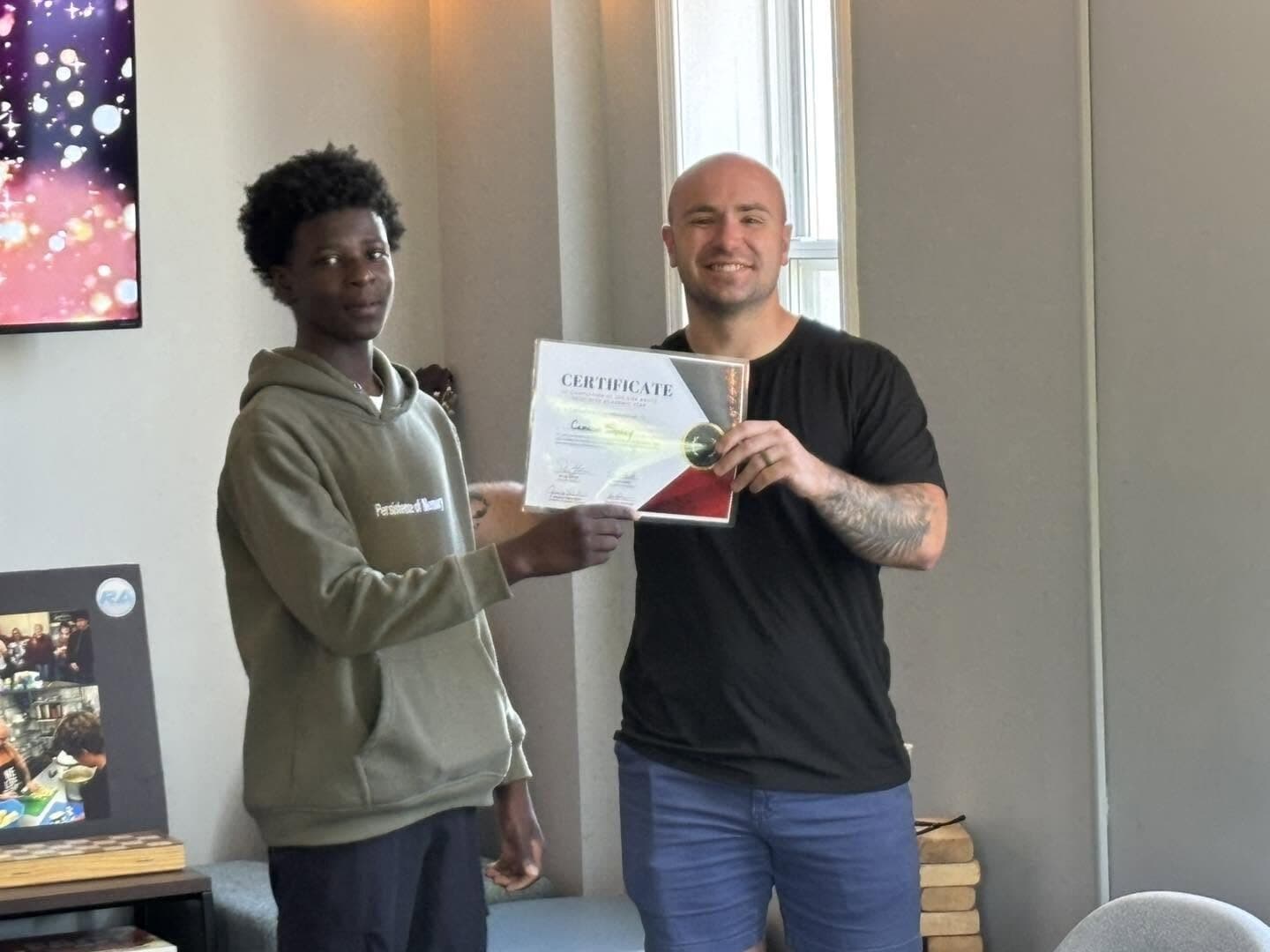 A Rise Above student holding a certificate alongside a staff member