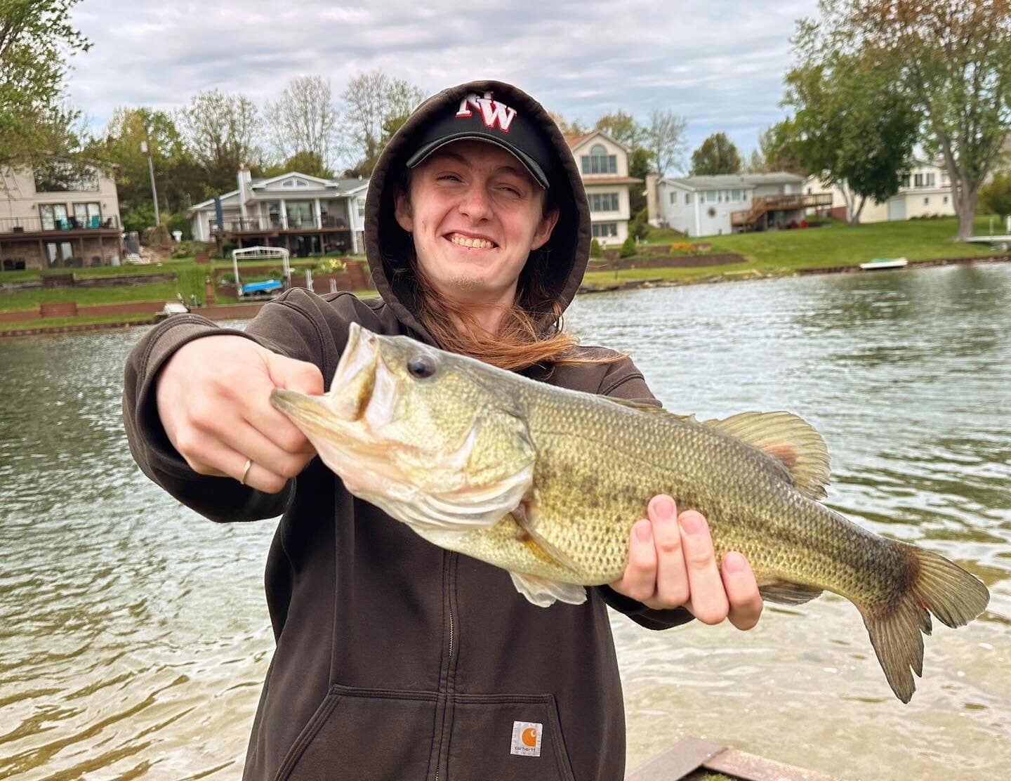 A Rise Above student holding up a largemouth bass by the lake
